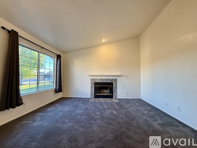 A spacious living room with a fireplace and large windows.