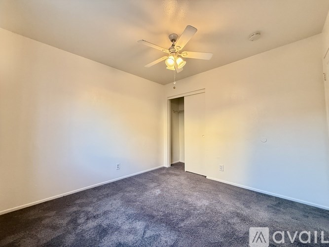 A room with a ceiling fan and carpeted floor.