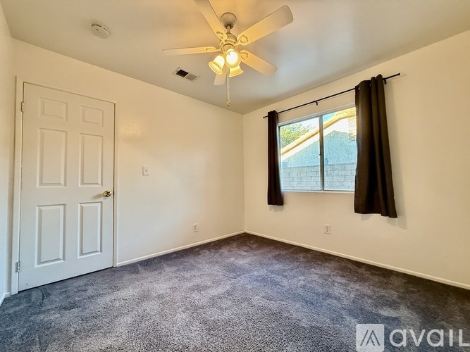A room with a ceiling fan and a door.