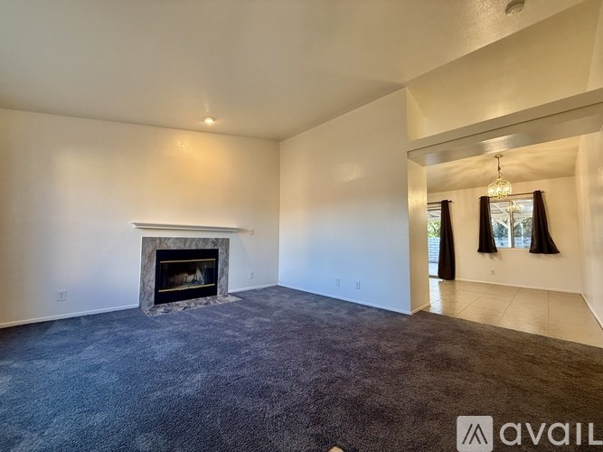 A living room with a fireplace and carpeted floor.