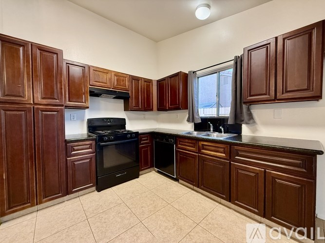 A kitchen with brown cabinets and black appliances.