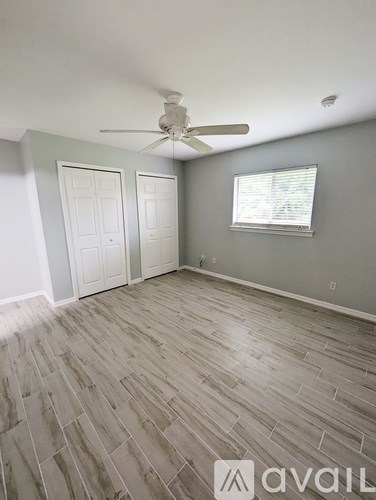 A room with a ceiling fan and wood flooring.