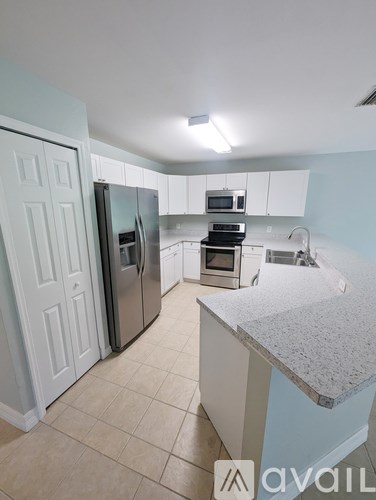 A kitchen with a refrigerator, microwave, oven, and sink.