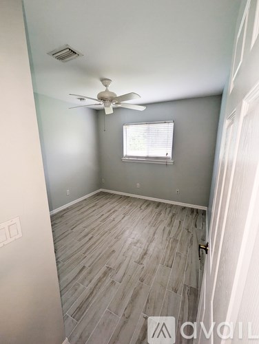 A room with a ceiling fan and a window with blinds.
