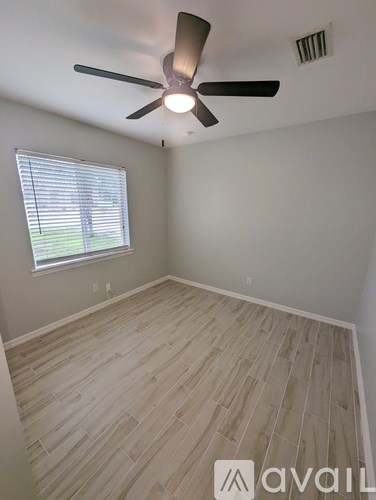 A room with a ceiling fan and a window with blinds.