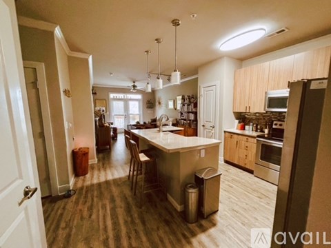 A kitchen with a large island in the middle and a dining area with chairs.