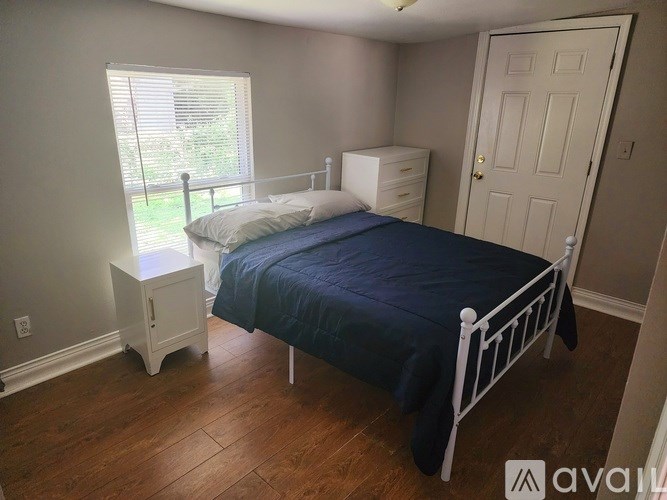 A bedroom with a bed, nightstand, and window.