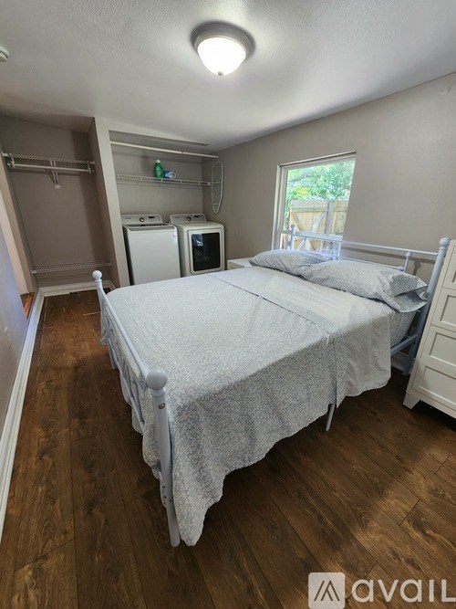 A bedroom with a bed, a microwave, and a window.