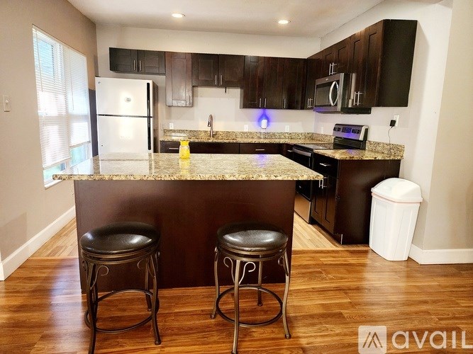 A kitchen with a granite countertop and two black stools.