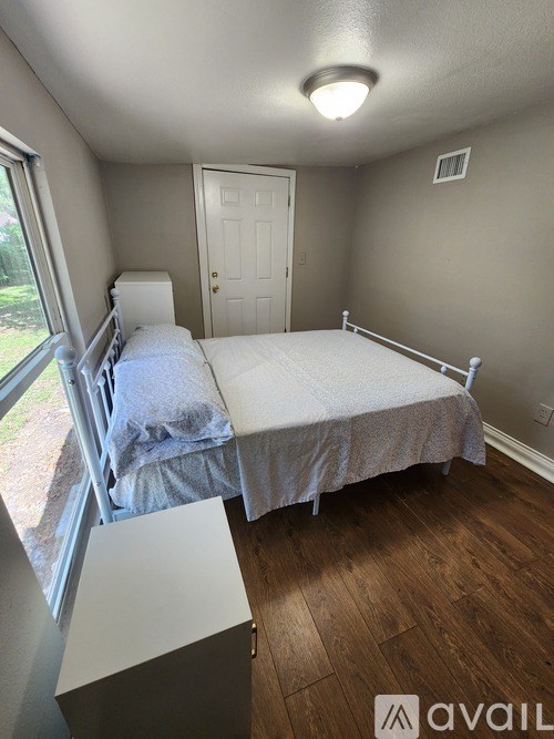 A bedroom with a bed, a window, and a door.