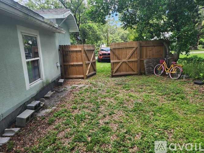 A backyard with a wooden fence and a bicycle leaning against it.