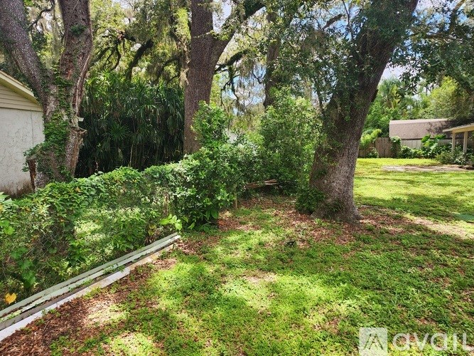 A lush green garden with a white fence and a tree in the center.