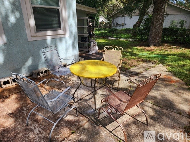 A yellow table and two chairs are on a patio.