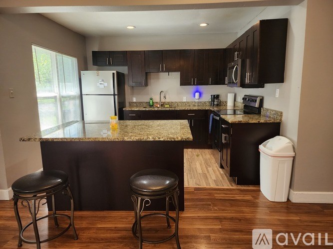 A kitchen with a granite countertop and bar stools.