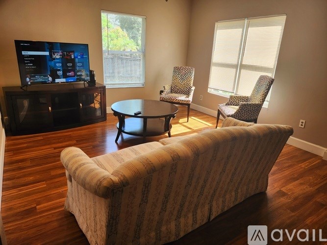 A living room with a television, two chairs, and a sofa.