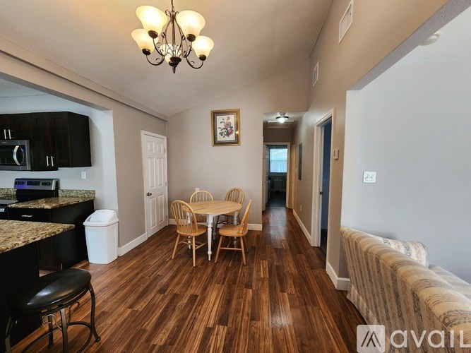 A living room with a wooden floor and a dining table with chairs.