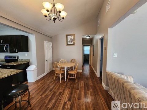 A living room with a wooden floor and a dining table with chairs.