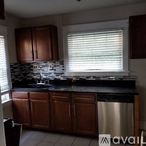 A kitchen with brown cabinets and a black countertop.