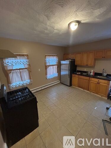 A kitchen with a black fridge and wooden cabinets.