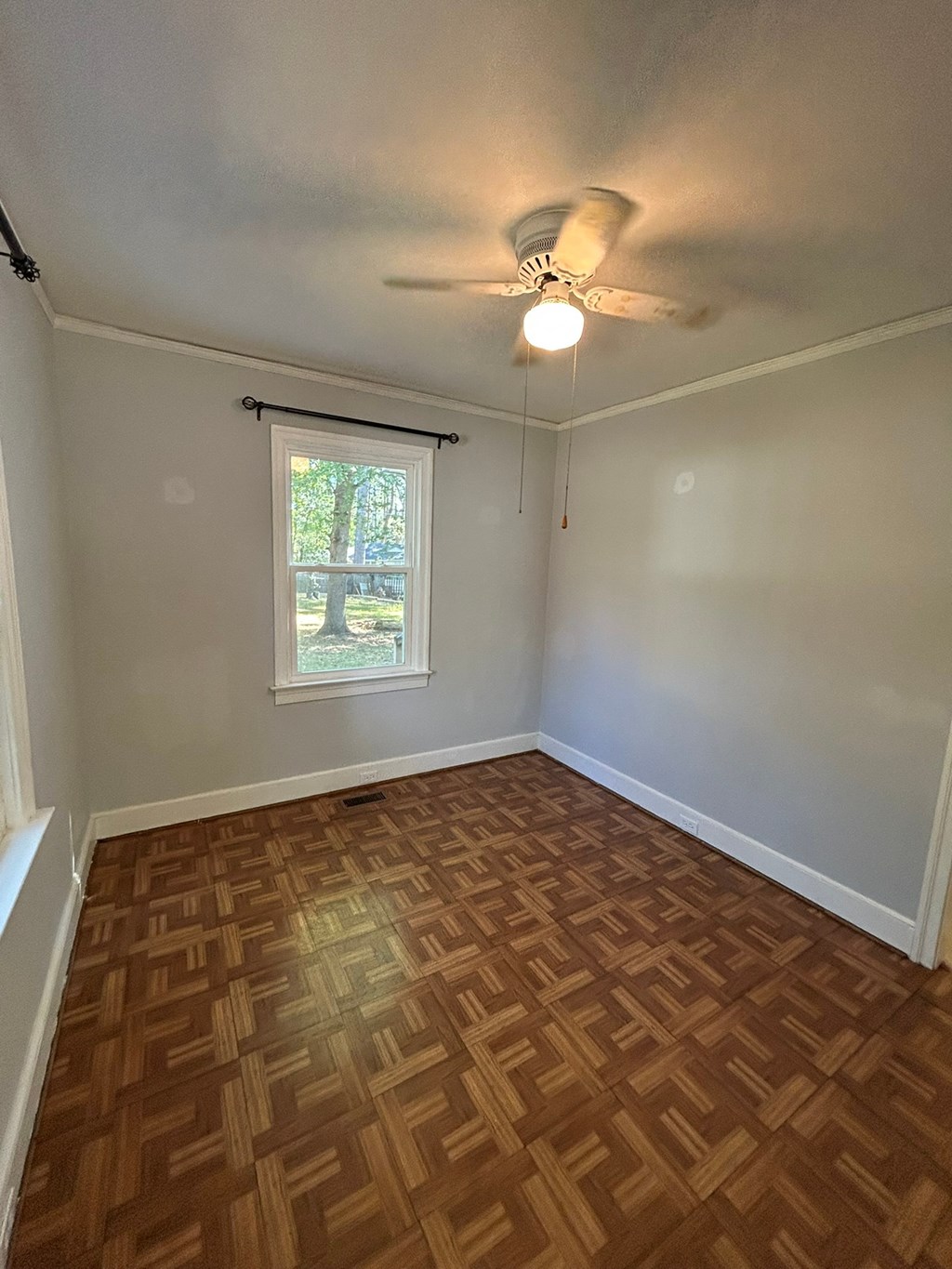 A room with a ceiling fan and a window with blinds.