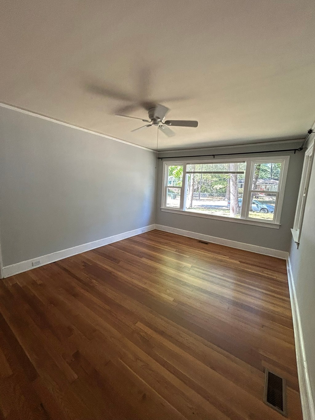 A room with a ceiling fan and wooden flooring.