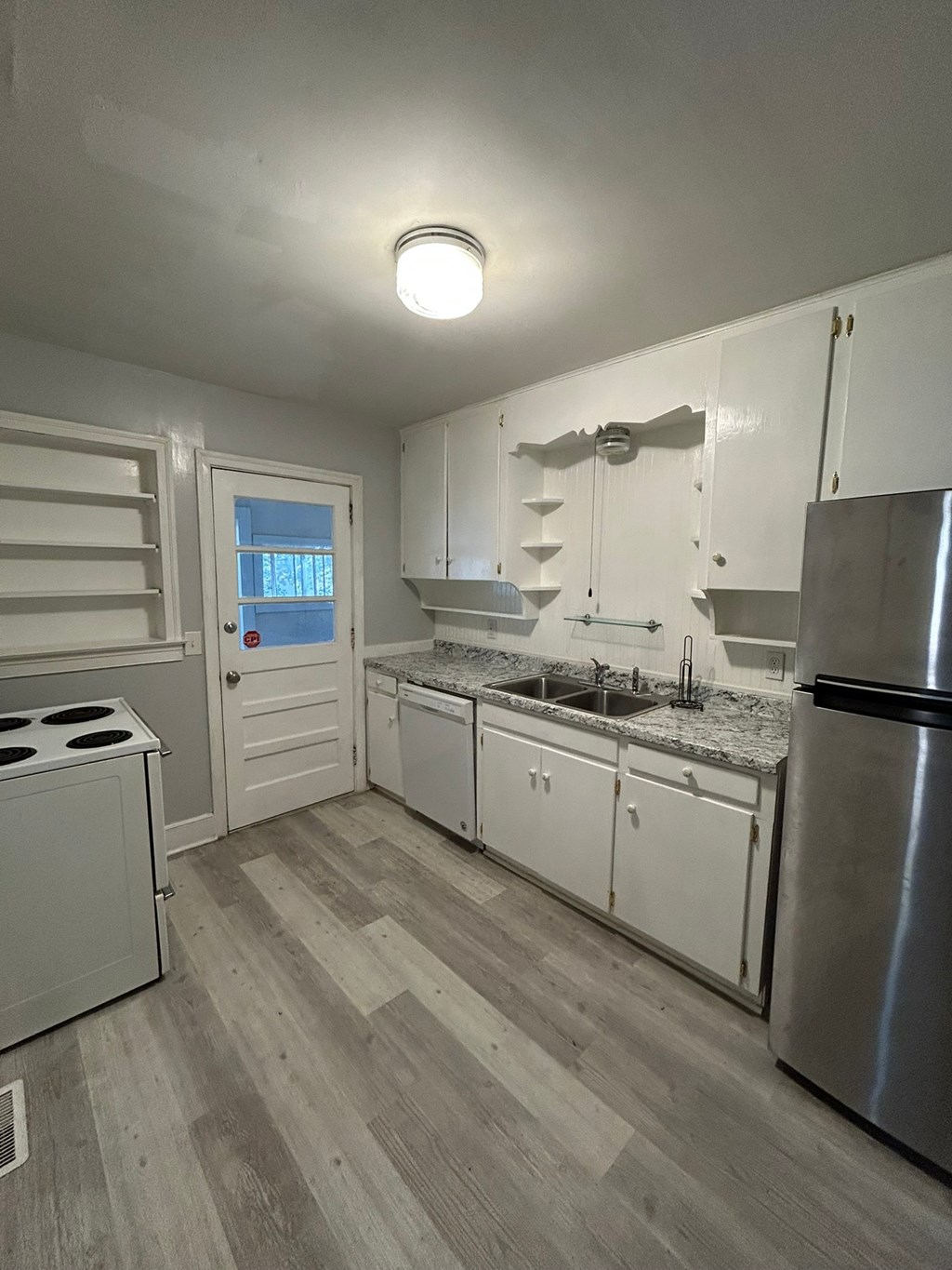 A kitchen with a stove, refrigerator, and sink.