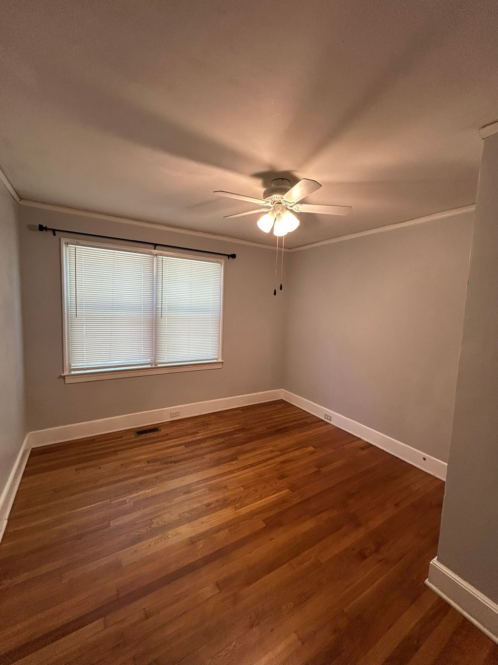 A room with a ceiling fan and wooden flooring.