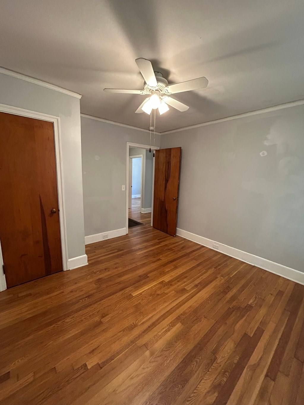 A room with a ceiling fan and wooden floors.