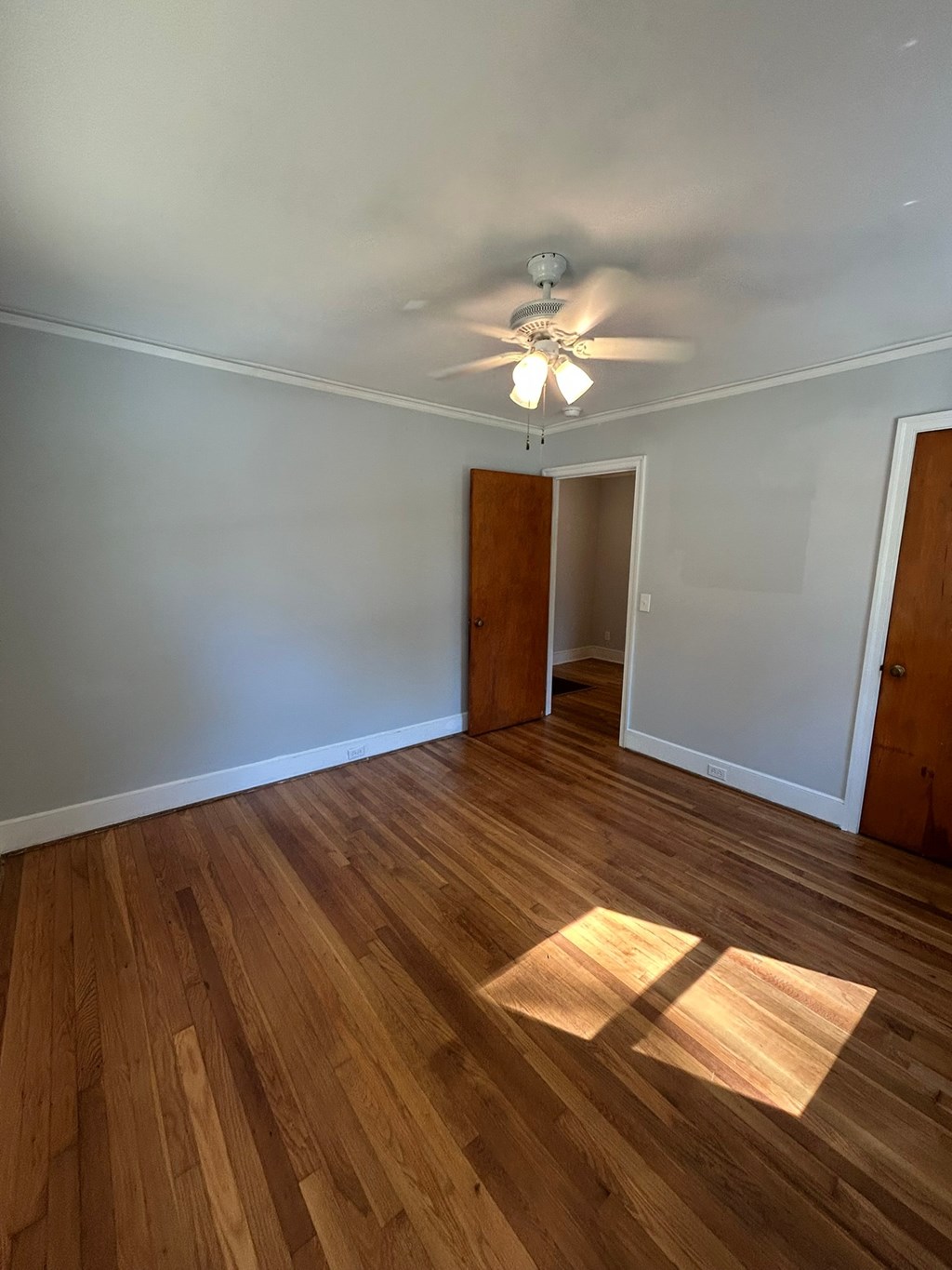 A room with wooden floors and a ceiling fan.