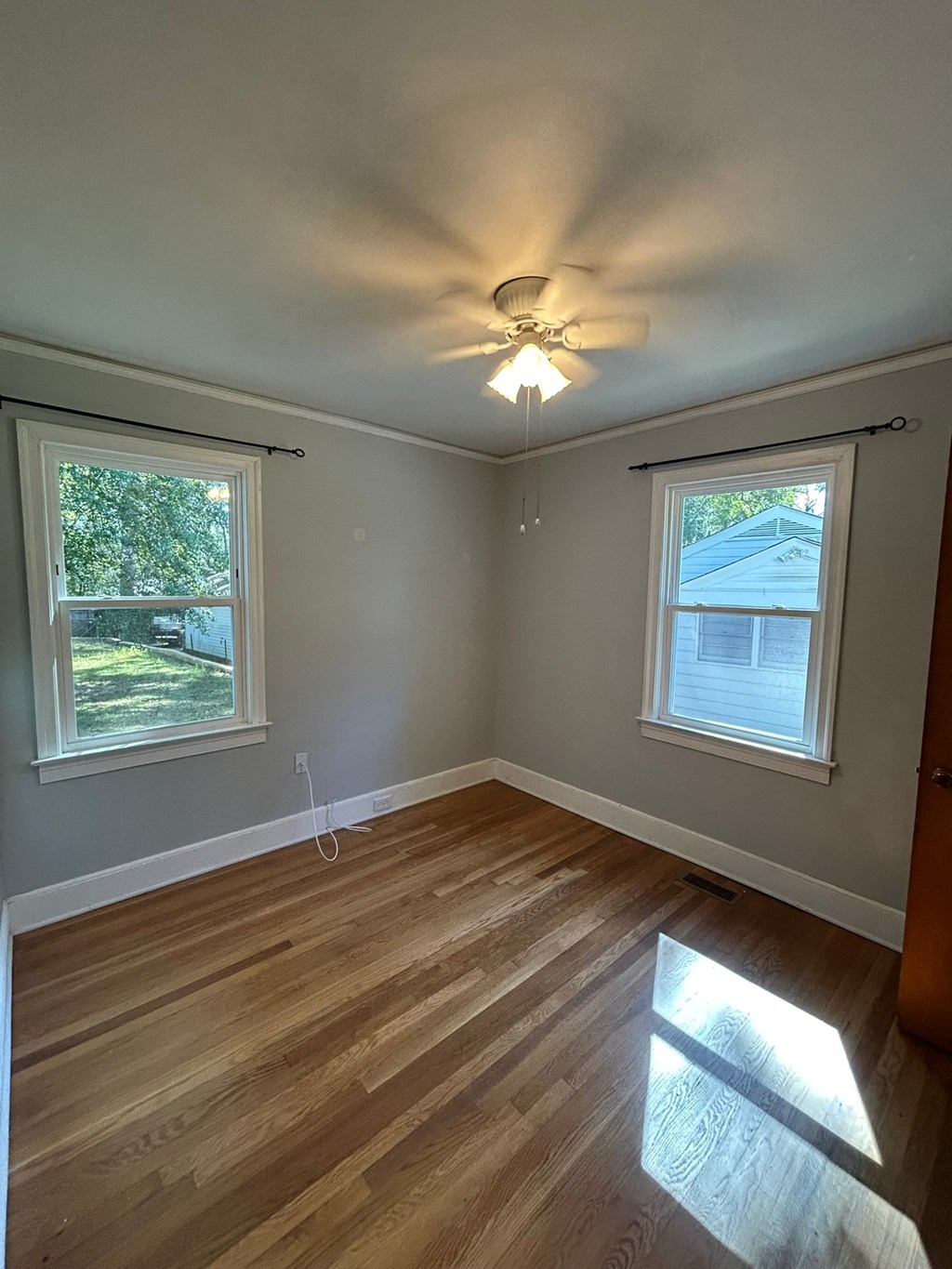 A room with wooden floors and a ceiling fan.