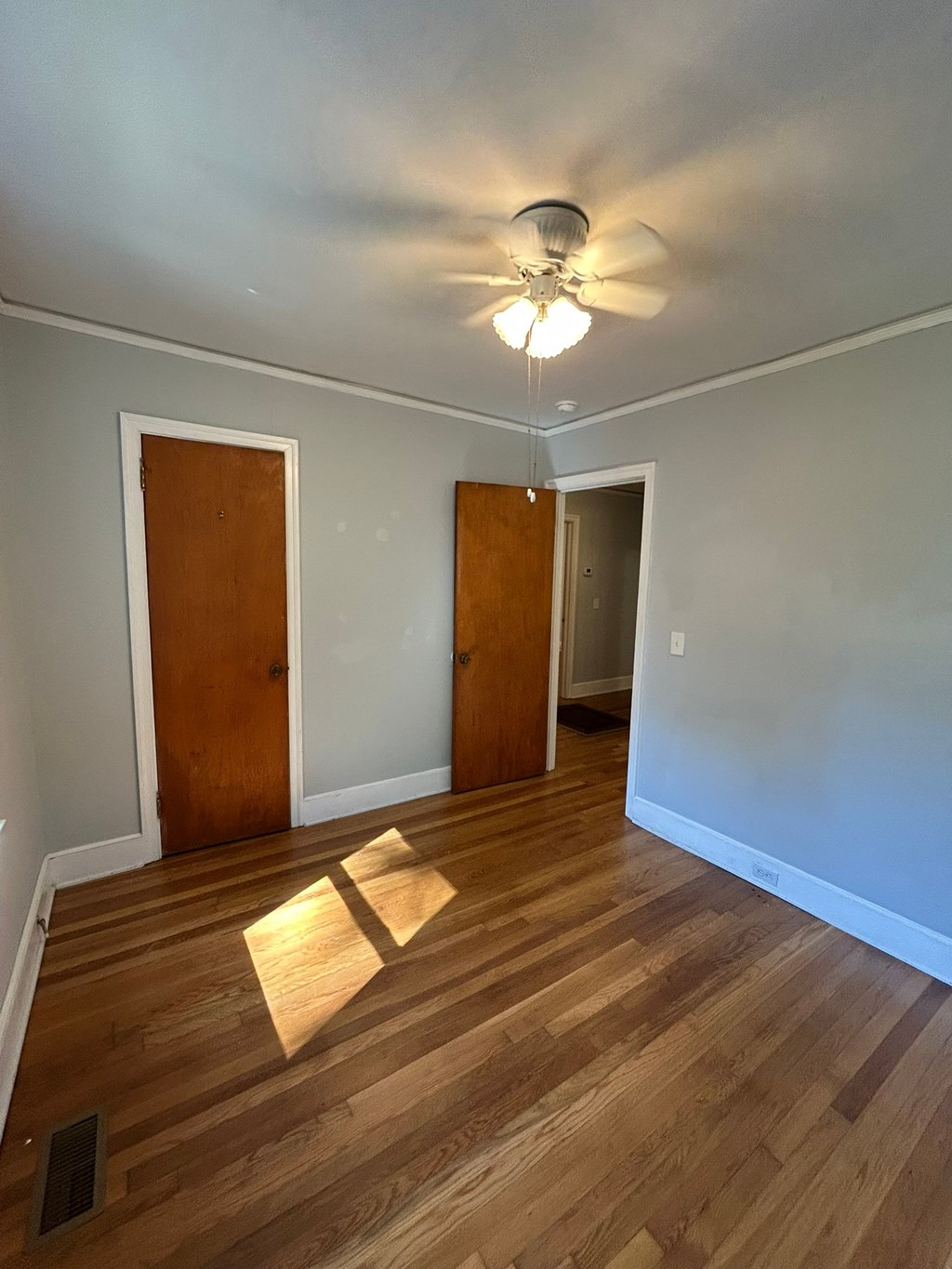 A room with wooden floors and a ceiling fan.