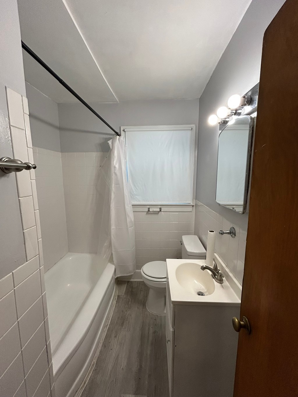 A white bathroom with a white toilet, white sink, and a white tub.