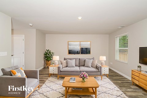 A living room with a grey couch, a wooden coffee table, and a painting on the wall.