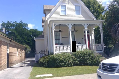 A white house with a black gate and a white picket fence.