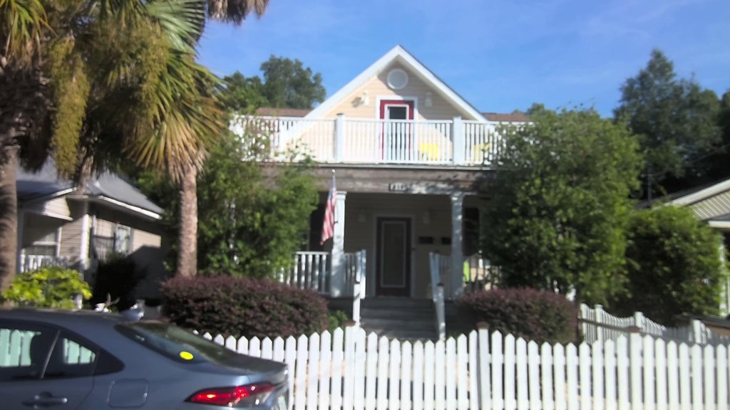 A house with a white picket fence and a car parked in front.