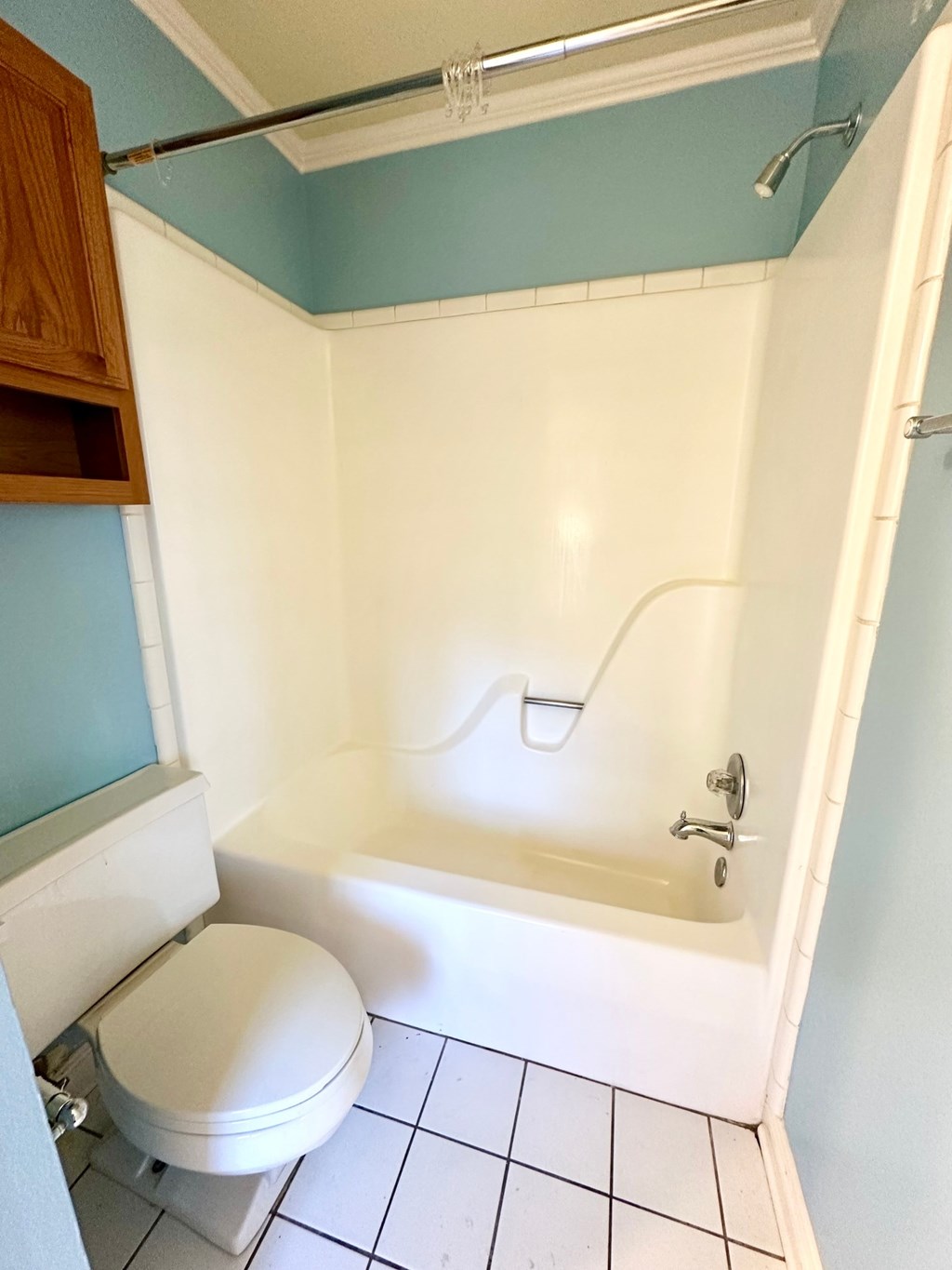 A white toilet sits next to a white bathtub in a small bathroom.