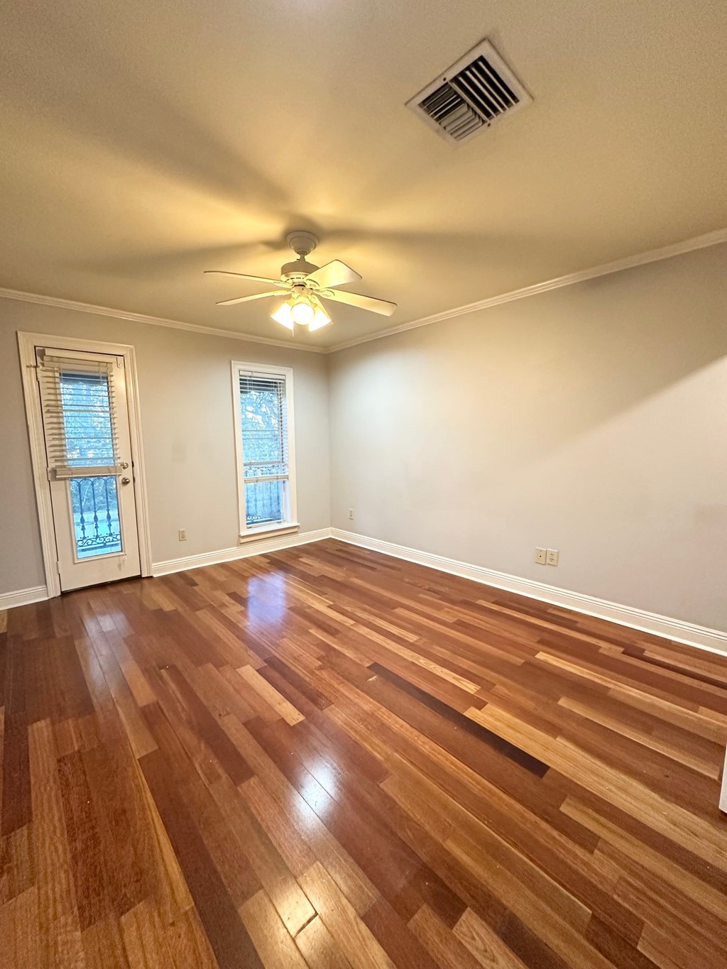 A room with a ceiling fan and wooden flooring.