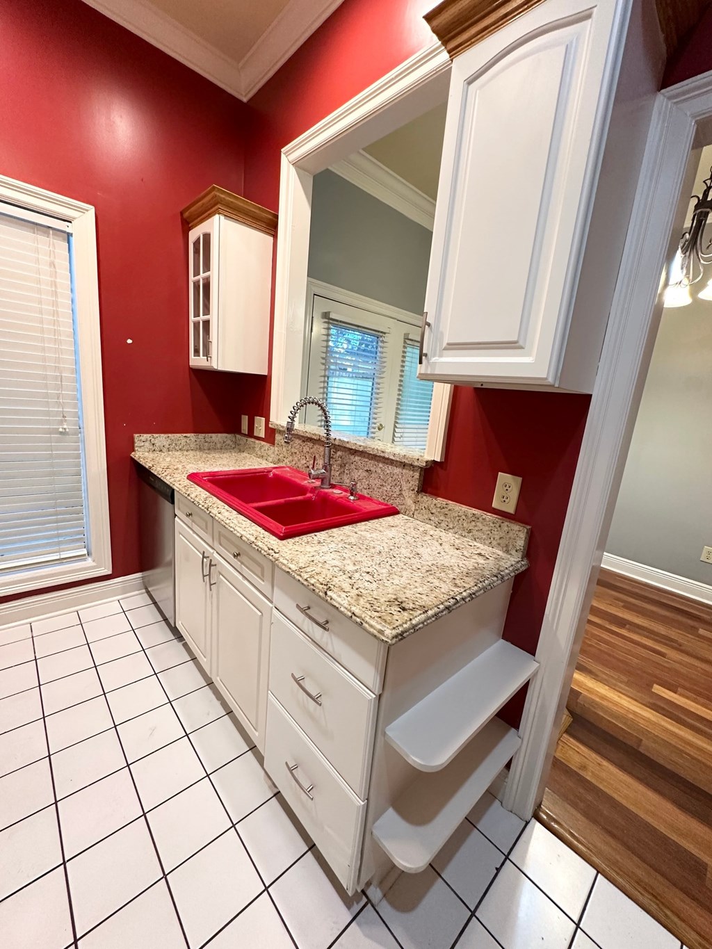 A kitchen with red walls and white cabinets.