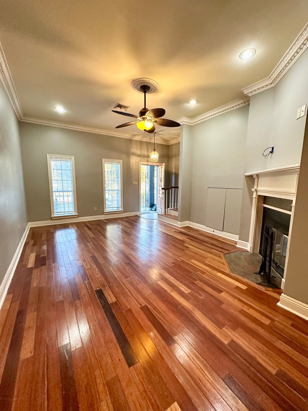 A room with wood flooring and a ceiling fan.