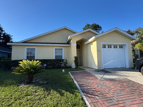 A house with a white garage door and a brick pathway leading to it.