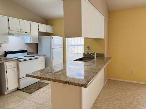 A kitchen with a granite countertop and white cabinets.