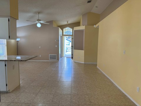 A spacious kitchen and living room with beige walls and tile flooring.