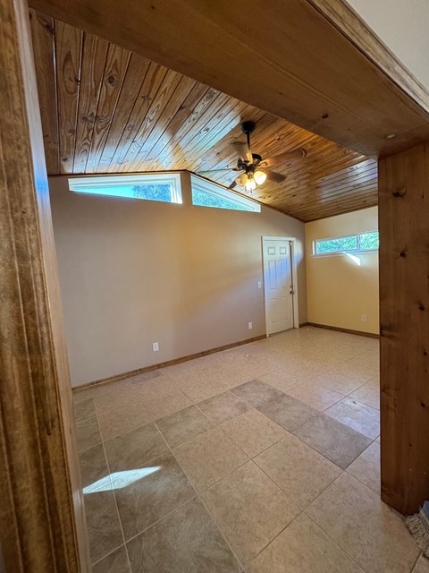 A room with wooden ceiling and tile flooring.