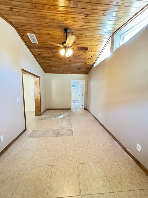 A room with wooden ceiling and tile floor.