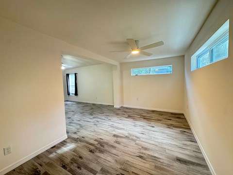 A room with a ceiling fan and a window with a view of trees.
