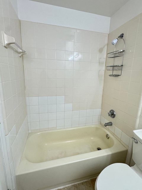 A white tiled bathroom with a claw foot tub.
