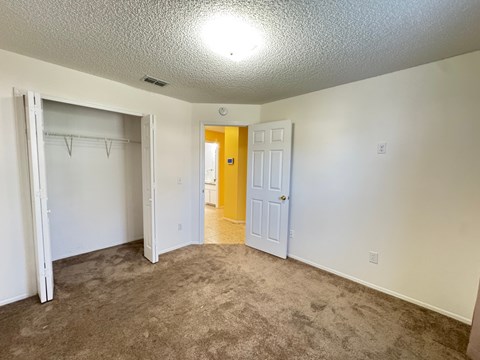 A room with a carpeted floor and a yellow door.
