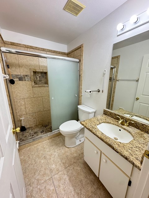 A bathroom with a toilet, sink, and shower.