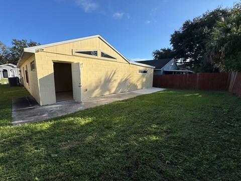 A small building with a yellow exterior is surrounded by a grassy area.