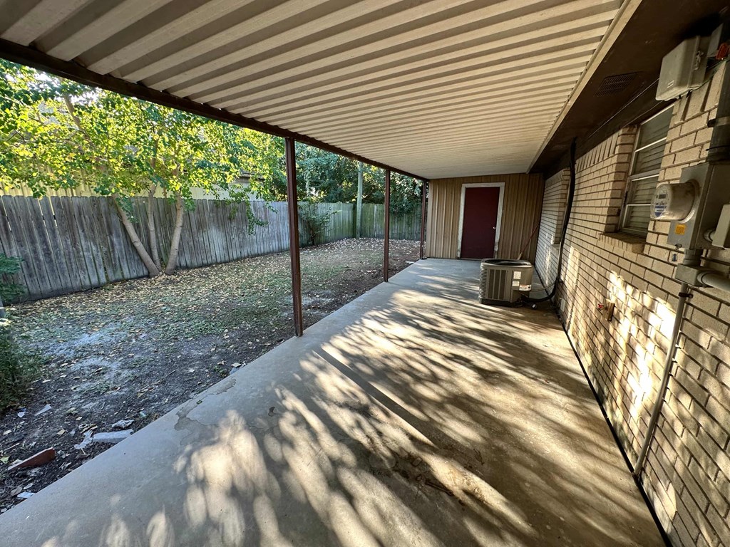 A patio with a red door and a wooden fence.